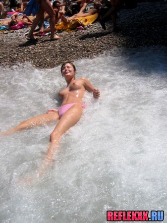 Сняв лифчик, с голыми сиськами по пляжу